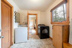 Laundry room featuring washing machine and clothes dryer and light tile patterned floors