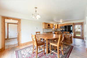 Dining space with baseboards, a chandelier, and light wood-style floors