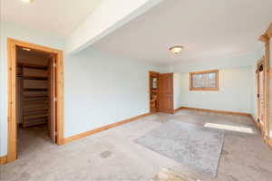 Unfurnished bedroom with light colored carpet, a spacious closet, baseboards, and a closet