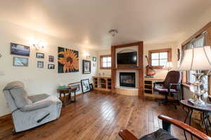 Living area featuring wood-type flooring, healthy amount of natural light, and a fireplace