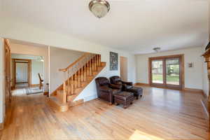 Living room with light wood-type flooring, stairs, and baseboards