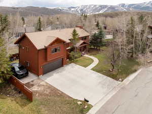 View of front of house featuring driveway, a mountain view, a garage, and a shingled roof