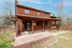 Rear view of house with a fenced backyard, a deck, and a chimney