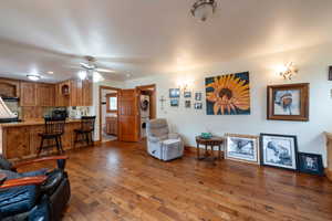 Living area with stacked washer / drying machine, hardwood / wood-style floors, ceiling fan, and baseboards