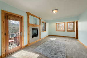 Unfurnished living room with carpet flooring, a fireplace, and baseboards
