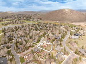 Aerial view of property and surrounding area featuring property parcel outlined, nearby suburban area, and a mountainous background