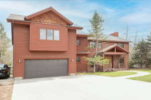 Chalet / cabin featuring a garage, concrete driveway, and a chimney