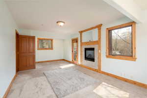 Unfurnished living room with carpet floors, a tile fireplace, and baseboards