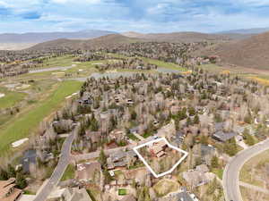 Aerial view of property and surrounding area with property boundaries highlighted, a local golf course, nearby suburban area, and a water and mountain view
