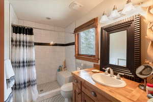 Bathroom with a tile shower, vanity, and toilet