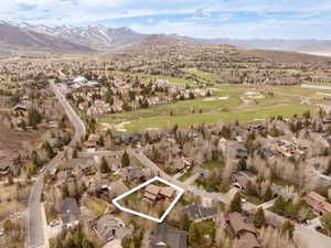 View of property location featuring property parcel outlined, a local golf course, mountains, and nearby suburban area