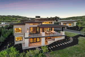 Back of property with a balcony, a patio area, and stone siding