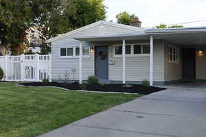 View of front of home featuring concrete driveway, a carport, and a chimney