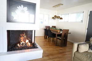 Dining area featuring wood finished floors, a brick fireplace, and baseboards