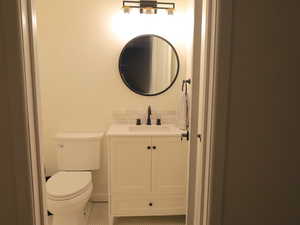Half bath with vanity, toilet, tile patterned floors, and tasteful backsplash