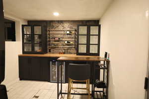 Indoor dry bar featuring wine cooler and recessed lighting