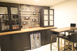 Indoor dry bar featuring beverage cooler and wallpapered walls