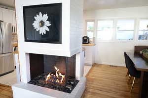 Dining space featuring a fireplace, light wood finished floors, and baseboards