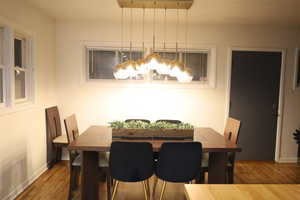 Dining area featuring wood finished floors, a chandelier, and baseboards