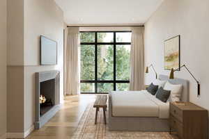 Bedroom with light wood-style floors, a warm lit fireplace, a wall of windows, and baseboards