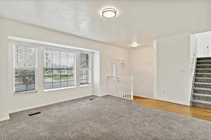 Unfurnished room featuring carpet flooring, baseboards, and stairs