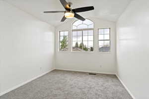 Carpeted spare room with ceiling fan, healthy amount of natural light, vaulted ceiling, and baseboards