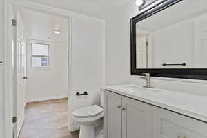 Bathroom with vanity, toilet, and baseboards