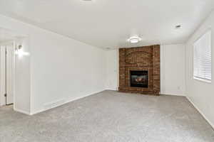 Unfurnished living room with carpet, a brick fireplace, and baseboards