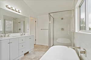 Bathroom featuring a soaking tub, a shower stall, double vanity, and lofted ceiling