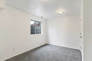 Spare room with dark colored carpet and baseboards