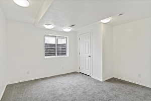 Carpeted empty room featuring baseboards, a smoke detector, and a textured ceiling