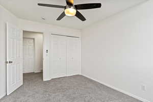 Unfurnished bedroom with carpet flooring, baseboards, a closet, and ceiling fan