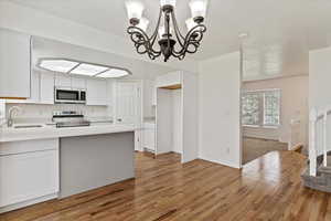 Kitchen featuring appliances with stainless steel finishes, a sink, light wood-type flooring, and white cabinetry