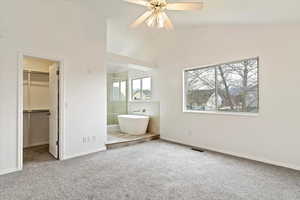 Unfurnished bedroom featuring a walk in closet, carpet, baseboards, and high vaulted ceiling