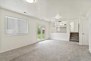 Carpeted spare room with stairs and baseboards