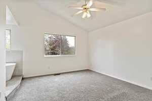 Unfurnished room featuring carpet flooring, a ceiling fan, lofted ceiling, and baseboards