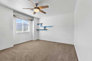 Carpeted spare room featuring a ceiling fan and a textured ceiling