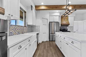 Kitchen with beamed ceiling, recessed lighting, appliances with stainless steel finishes, backsplash, and white cabinetry