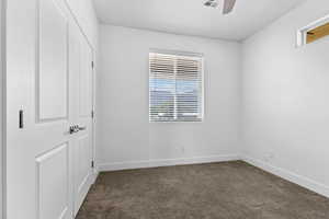 Unfurnished bedroom with dark carpet and ceiling fan