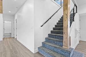 Staircase with wood finished floors and recessed lighting