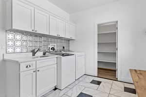 Washroom featuring washer and clothes dryer and cabinet space