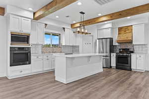 Kitchen with beamed ceiling, appliances with stainless steel finishes, recessed lighting, light countertops, and white cabinetry