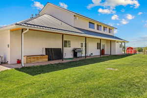 Back of house featuring a yard, a patio area, metal roof, and stucco siding