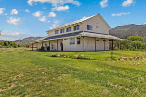 Back of house with a mountain view, a lawn, and metal roof
