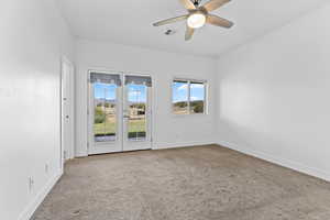 Carpeted spare room with ceiling fan and baseboards