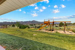 View of green lawn with a playground and a mountain view