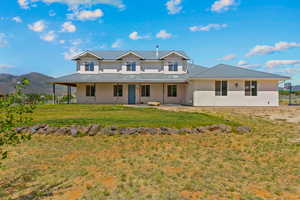 Rear view of house featuring stucco siding, metal roof, a yard, and a mountain view