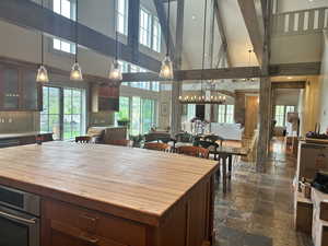 Kitchen featuring high vaulted ceiling, stone tile floors, stainless steel oven, butcher block counters, and tasteful backsplash