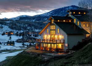 Snow covered back of property featuring a mountain view, a balcony, and a patio area