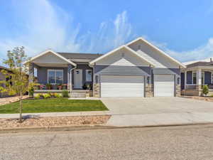 Craftsman house featuring a garage, covered porch, concrete driveway, a front yard, and stone siding